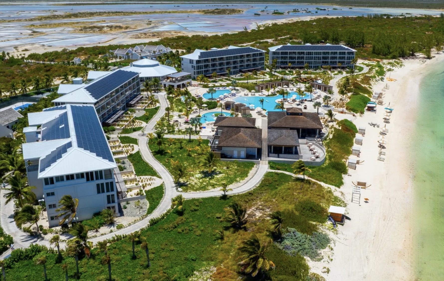 Aerial view of Salterra Resort on South Caicos, with rooftop solar panels covering four buildings beside the beach